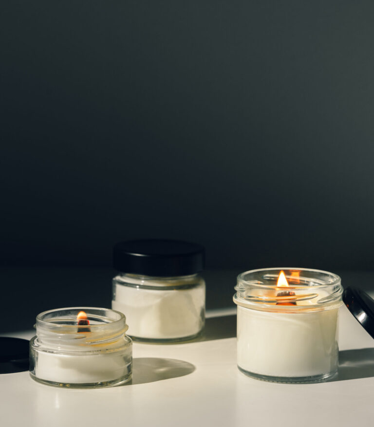 Scented Candles Burning On White Surface With Black Background close up